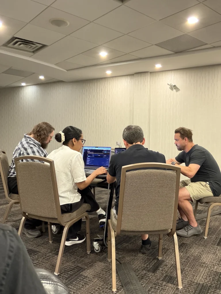 Four people building together around a table with laptops